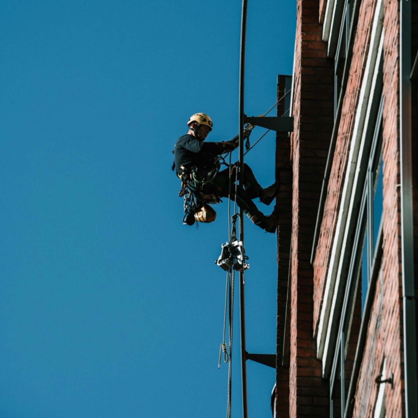 Ein Arbeiter klettert an einer Fassade eines Gebäudes in klarer Himmel Höhenarbeit Höhe Klettern Kletterer Seil Industrieklettern Ausrüstung