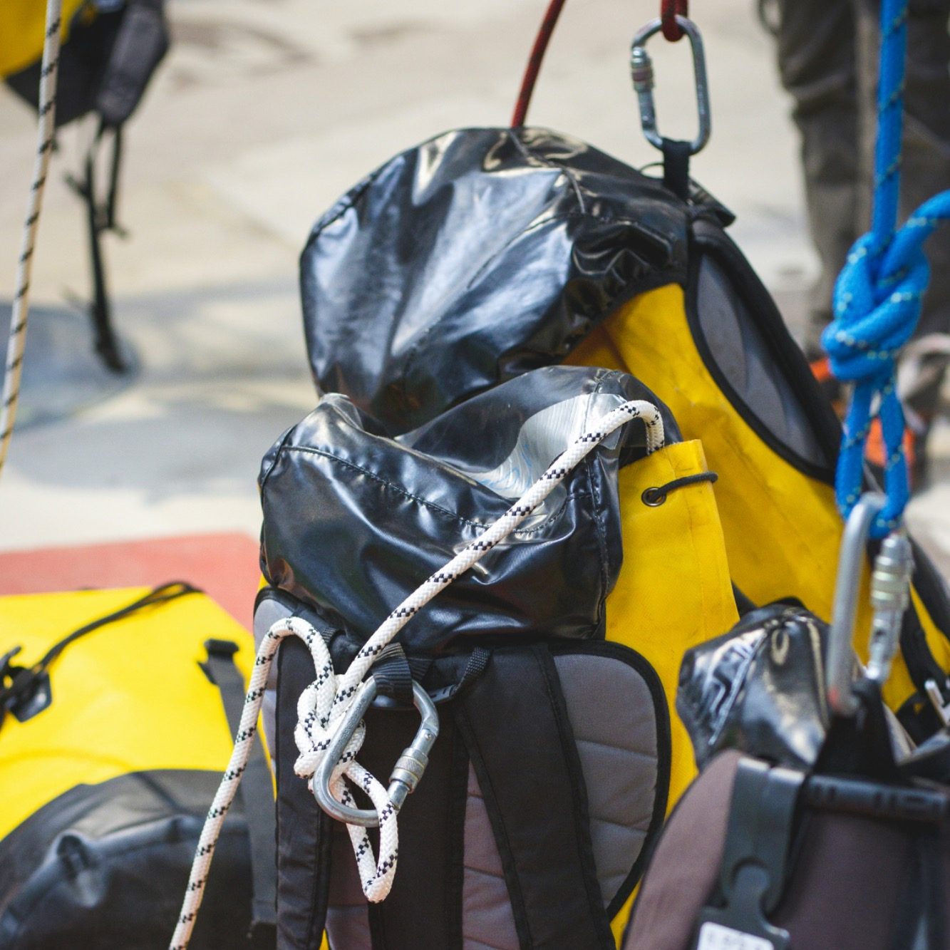 Ausrüstung Kletterausrüstung Seile Karabiner Prüfung DGUV Gelbe Rucksäcke mit Sicherheitsausrüstung und Seilen in einem Outdoor-Umfeld.