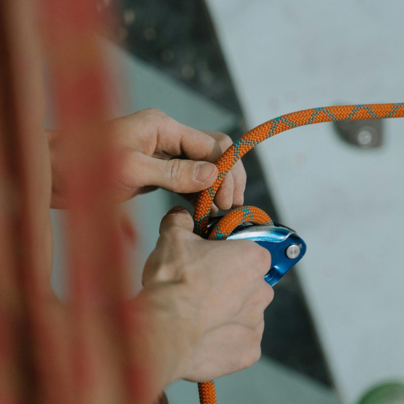 Hände halten ein Klettergerät und eine orangefarbene Kletterseil.
Kletterseil Karabiner Prüfung Absturzsicherung DGUV